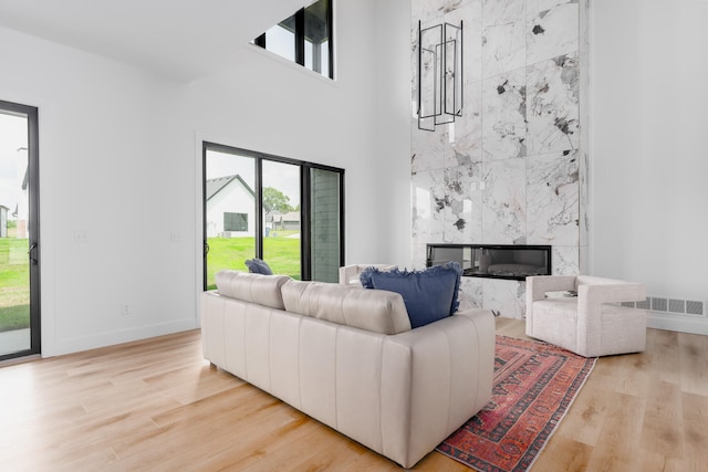 living room featuring light hardwood / wood-style flooring, a wealth of natural light, and a high end fireplace