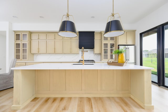 kitchen with light wood-style floors, light countertops, high quality fridge, and glass insert cabinets