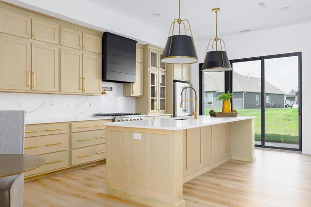 kitchen featuring premium range hood, a sink, light wood-style floors, light countertops, and light brown cabinetry