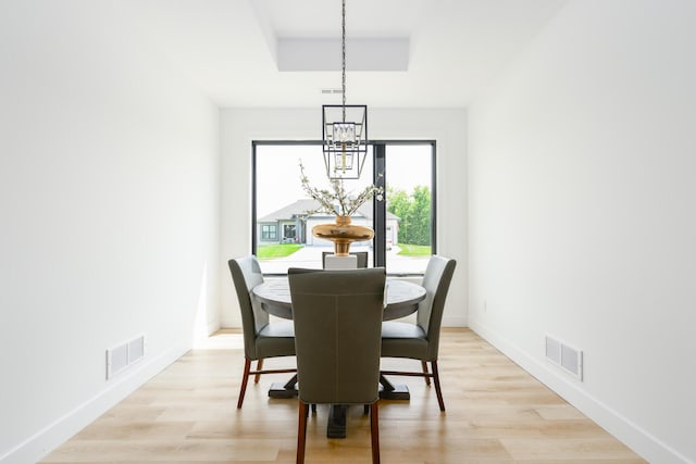 dining space featuring light wood-style flooring, visible vents, and baseboards