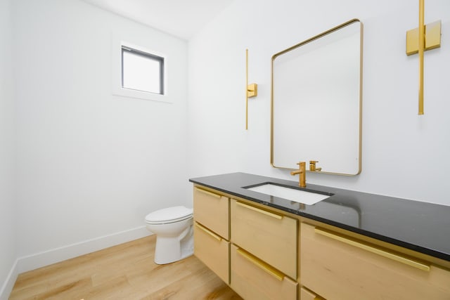 bathroom featuring baseboards, vanity, toilet, and wood finished floors