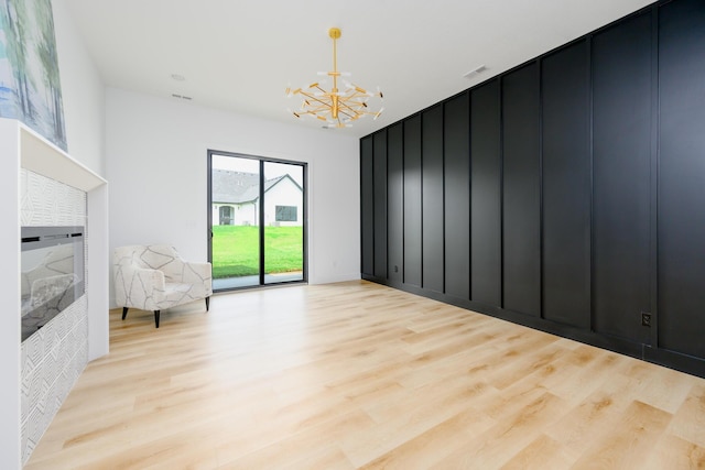 unfurnished room with a chandelier, light wood finished floors, and visible vents