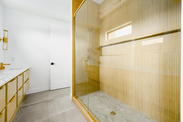 bathroom featuring double vanity, a stall shower, a sink, and tile patterned floors