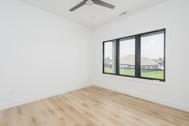 spare room with ceiling fan, light wood-style flooring, visible vents, and baseboards