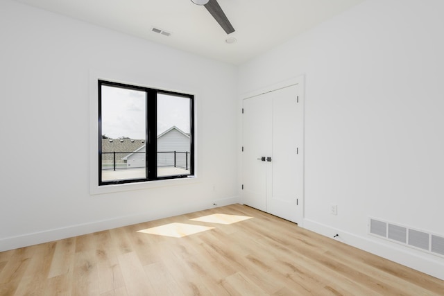 spare room featuring baseboards, visible vents, and wood finished floors