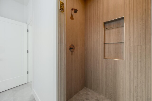 bathroom with tiled shower and tile patterned flooring