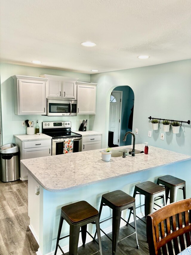 kitchen featuring white cabinetry, stainless steel appliances, a kitchen breakfast bar, and light hardwood / wood-style floors