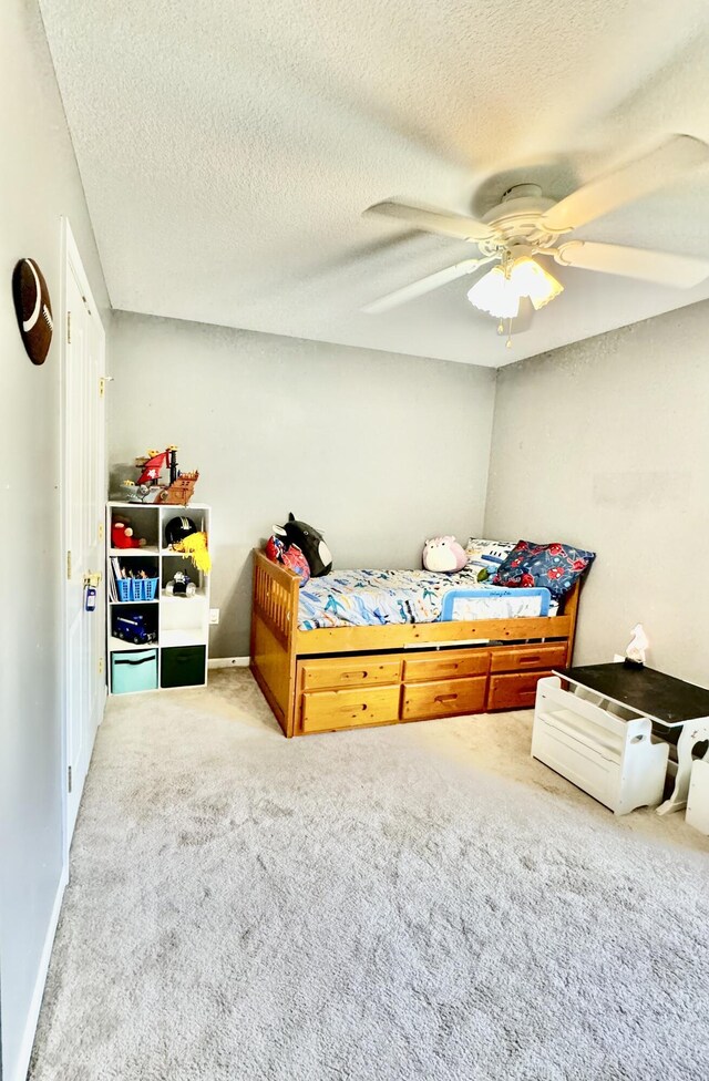 bedroom featuring ceiling fan, a textured ceiling, and carpet flooring