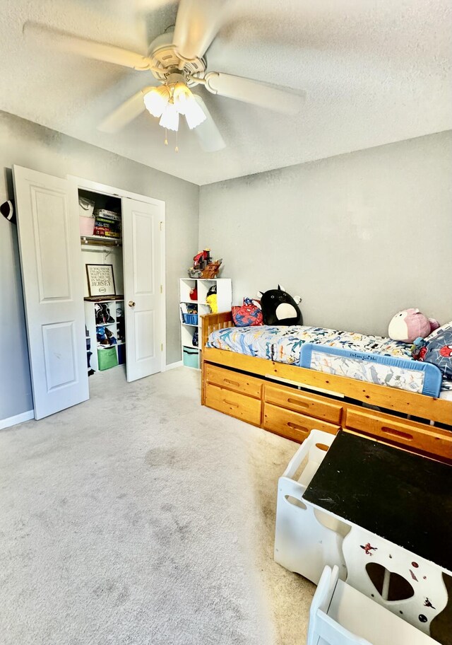 bedroom with ceiling fan, carpet flooring, and a textured ceiling