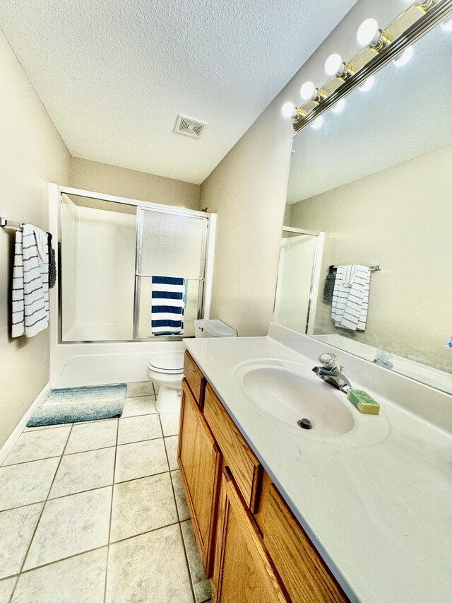 full bathroom with bathing tub / shower combination, tile patterned flooring, vanity, a textured ceiling, and toilet