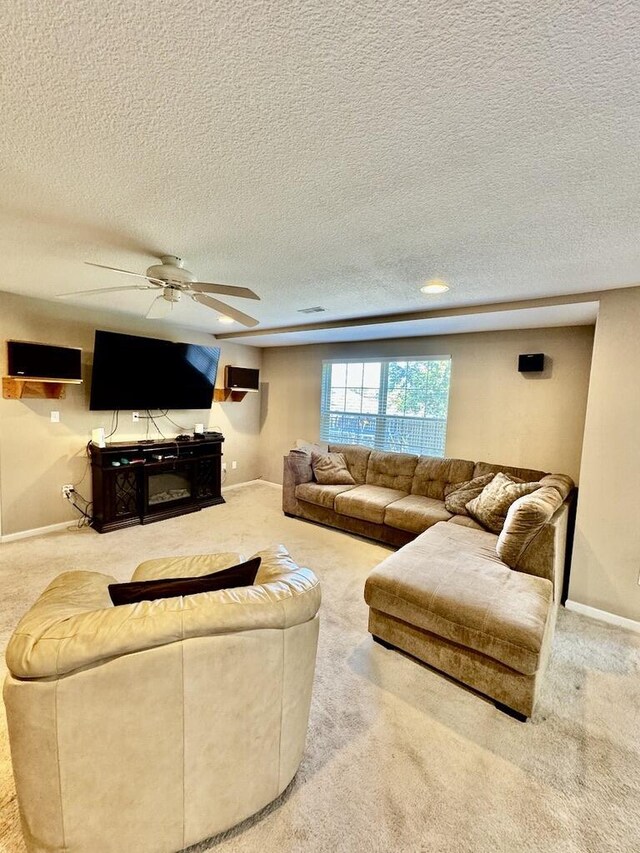 carpeted living room with ceiling fan and a textured ceiling