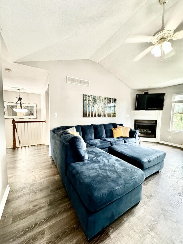 living room with ceiling fan, lofted ceiling, hardwood / wood-style floors, and a textured ceiling