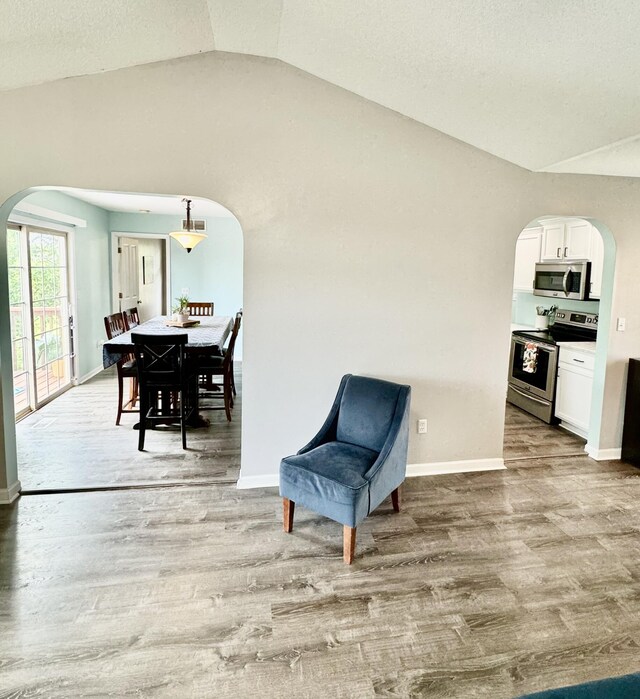 living area featuring lofted ceiling and light hardwood / wood-style flooring