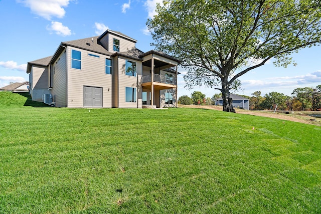 view of front of property with a balcony, a front yard, and central AC