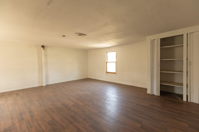 unfurnished bedroom with a textured ceiling and dark hardwood / wood-style floors