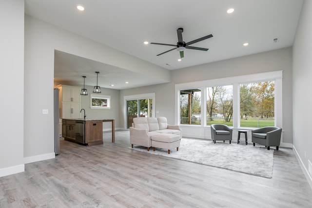 living room with ceiling fan, a wealth of natural light, sink, and light hardwood / wood-style floors