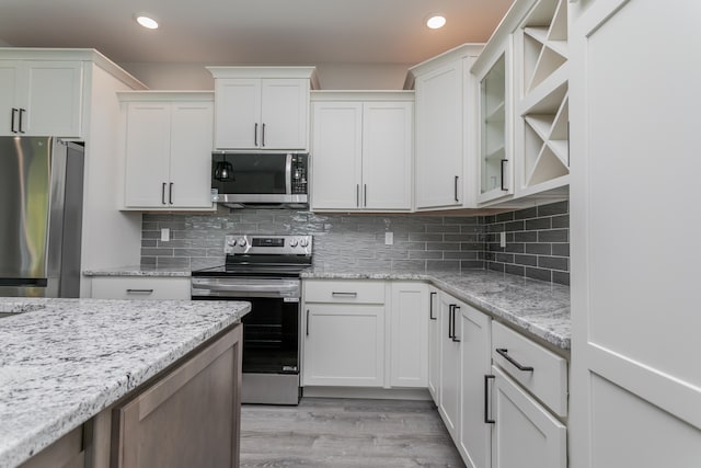 kitchen featuring white cabinetry, light wood-type flooring, stainless steel appliances, and tasteful backsplash