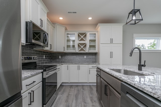 kitchen with white cabinetry, appliances with stainless steel finishes, sink, and light hardwood / wood-style flooring