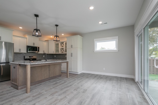 108 Lisa Ct, Hallsville, MO 65255 - kitchen with appliances with stainless steel finishes, backsplash, a kitchen island with sink, light wood finished floors, and light stone counters