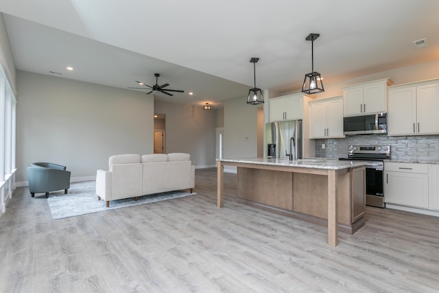 kitchen featuring stainless steel appliances, white cabinets, a kitchen island with sink, and light hardwood / wood-style flooring