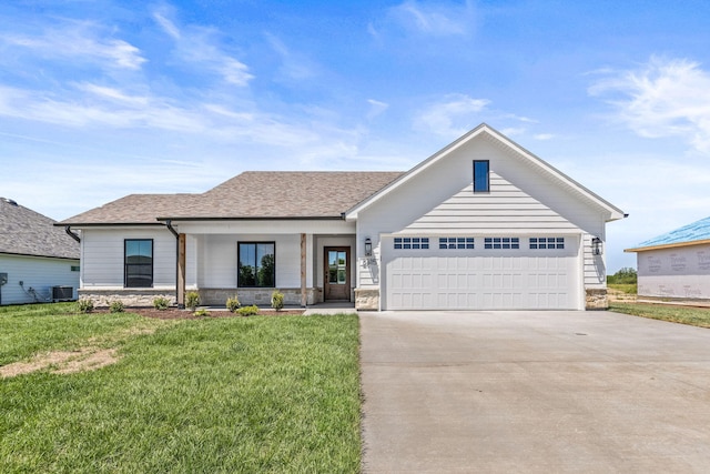 view of front of home featuring a garage, a front yard, and central AC