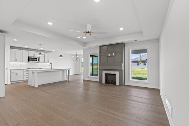 unfurnished living room featuring a large fireplace, a raised ceiling, and light hardwood / wood-style flooring