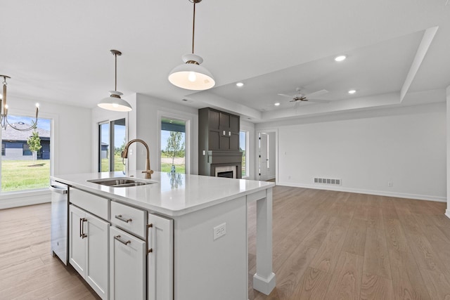 kitchen with white cabinetry, sink, pendant lighting, and a center island with sink