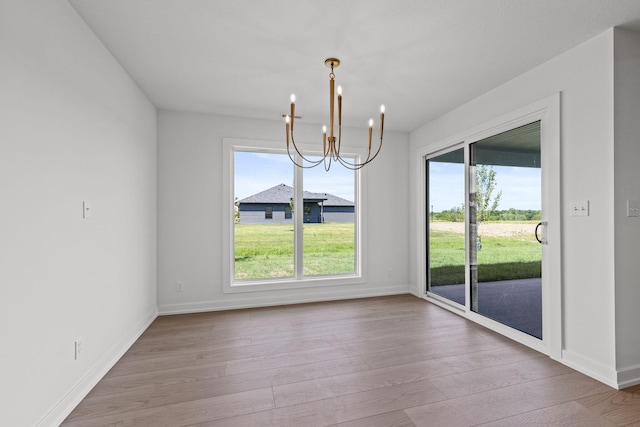 unfurnished dining area with a chandelier and light wood-type flooring