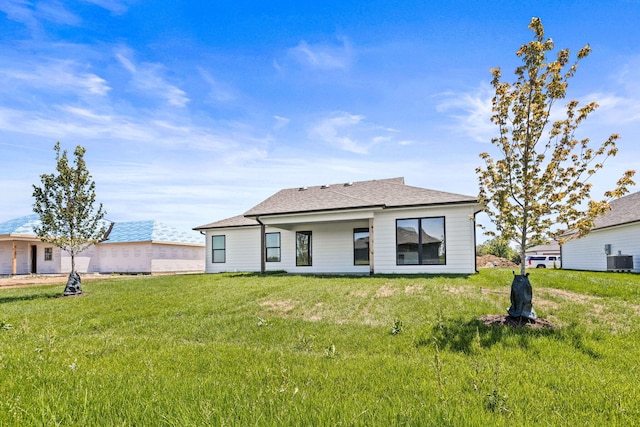 rear view of house featuring a lawn and central AC unit