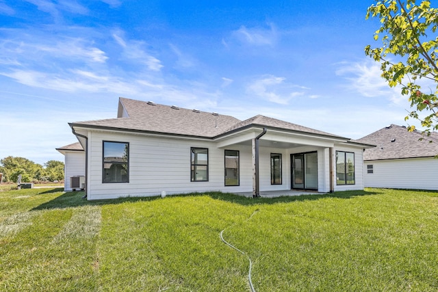 back of property with a lawn and central AC