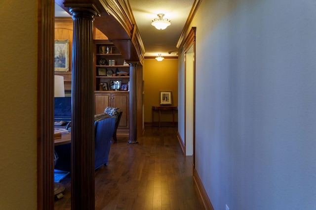 hall featuring dark hardwood / wood-style floors, ornate columns, built in features, and ornamental molding