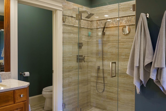 bathroom with vanity, a shower with shower door, and toilet