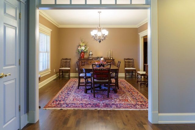 dining room with dark hardwood / wood-style flooring, crown molding, and an inviting chandelier