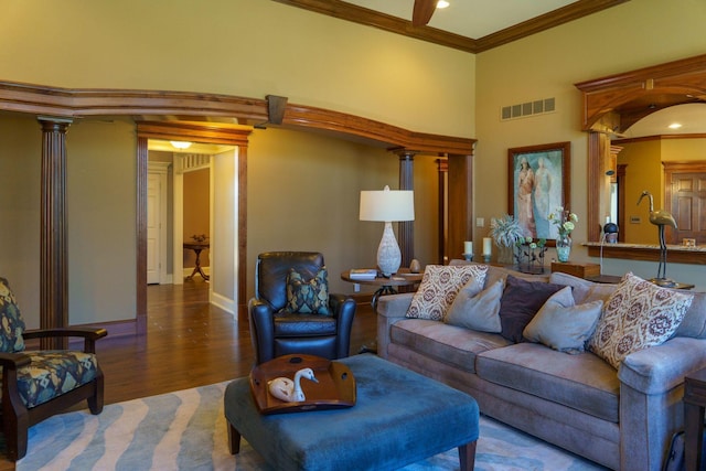 living room featuring hardwood / wood-style floors, crown molding, and ornate columns