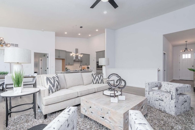 living room with ceiling fan, light hardwood / wood-style flooring, and a towering ceiling