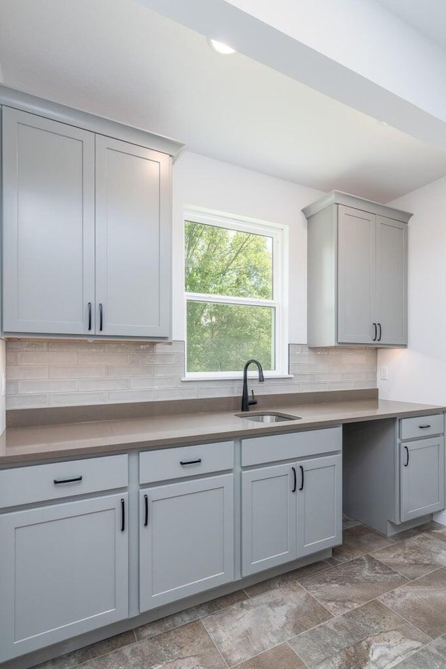 kitchen featuring backsplash, gray cabinetry, and sink