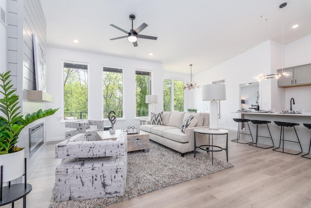 living room featuring sink, light hardwood / wood-style floors, and ceiling fan with notable chandelier