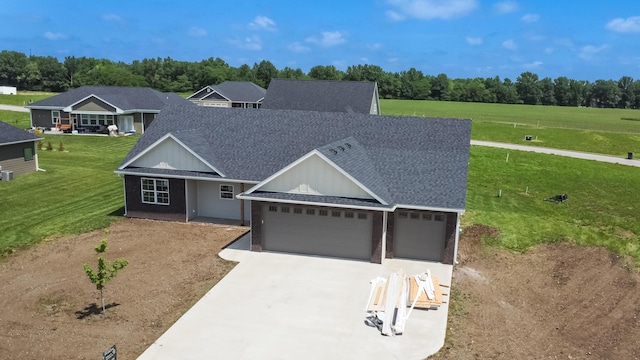 ranch-style home with an attached garage, a shingled roof, a front lawn, and concrete driveway