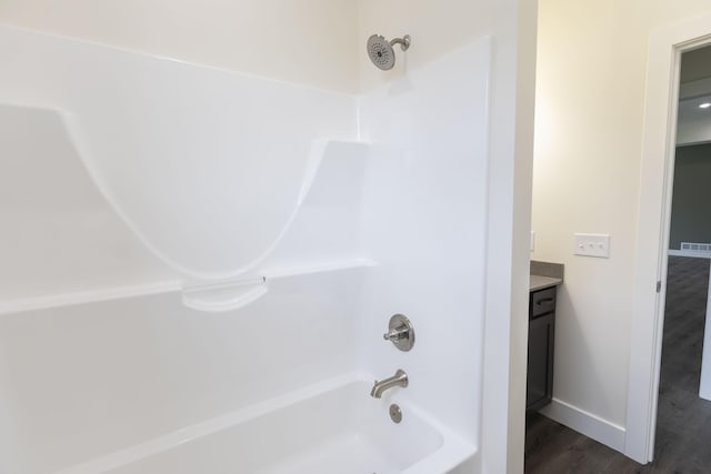 bathroom with visible vents, tub / shower combination, baseboards, wood finished floors, and vanity