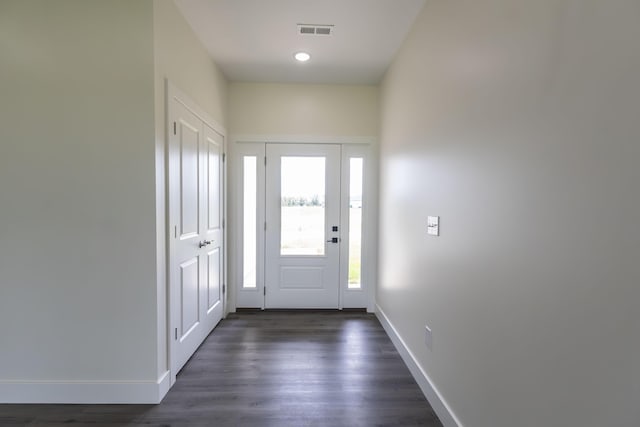 foyer entrance with dark wood-style floors, baseboards, and visible vents