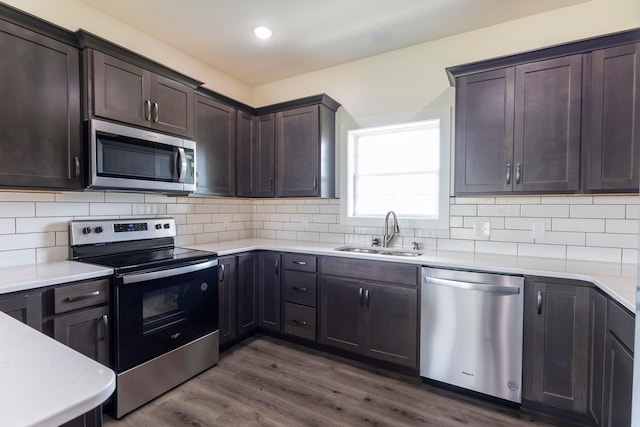 kitchen with stainless steel appliances, decorative backsplash, sink, dark hardwood / wood-style floors, and dark brown cabinetry