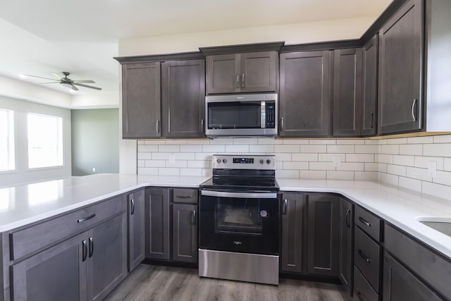 kitchen with dark wood-type flooring, a ceiling fan, appliances with stainless steel finishes, light countertops, and dark brown cabinets