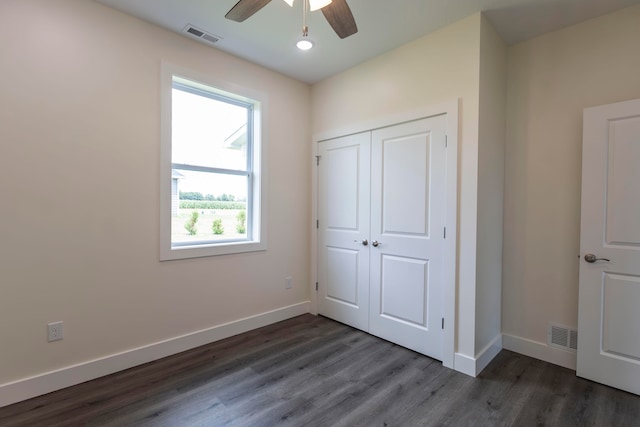 unfurnished bedroom with ceiling fan, dark hardwood / wood-style flooring, and a closet