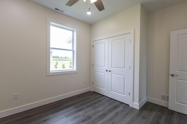 unfurnished bedroom with dark wood finished floors, visible vents, a closet, and baseboards