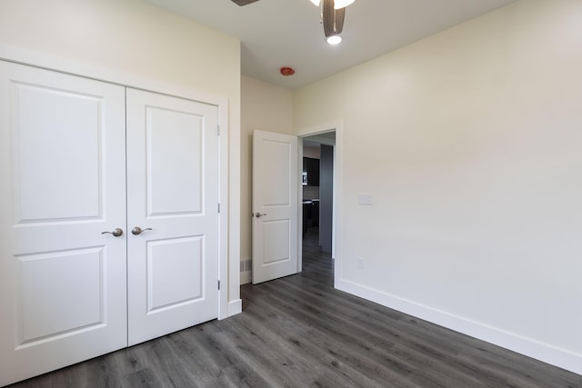 unfurnished bedroom featuring dark wood finished floors, baseboards, a closet, and ceiling fan