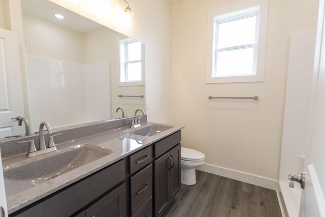 bathroom featuring double vanity, hardwood / wood-style floors, and toilet