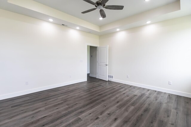 unfurnished room featuring dark hardwood / wood-style flooring, ceiling fan, and a tray ceiling