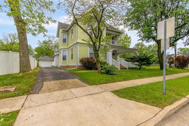 view of front of house with a front lawn, a balcony, an outdoor structure, and a garage