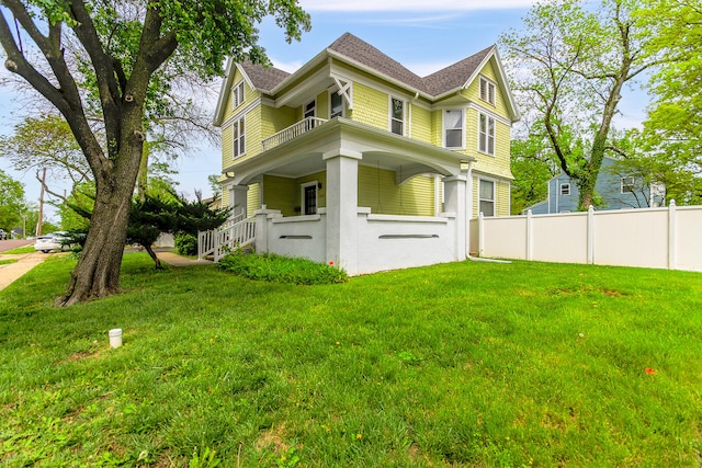 view of side of home featuring covered porch and a yard