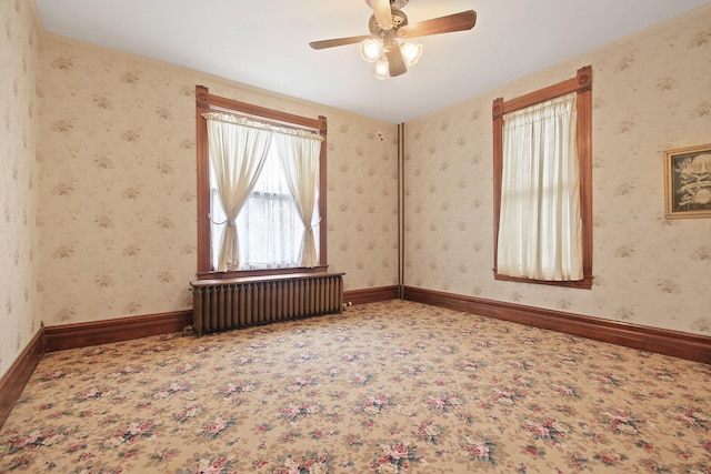 unfurnished room featuring ceiling fan and radiator